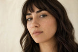 Adult model wearing one polished yellow-gold septum clicker in a premium beauty portrait.